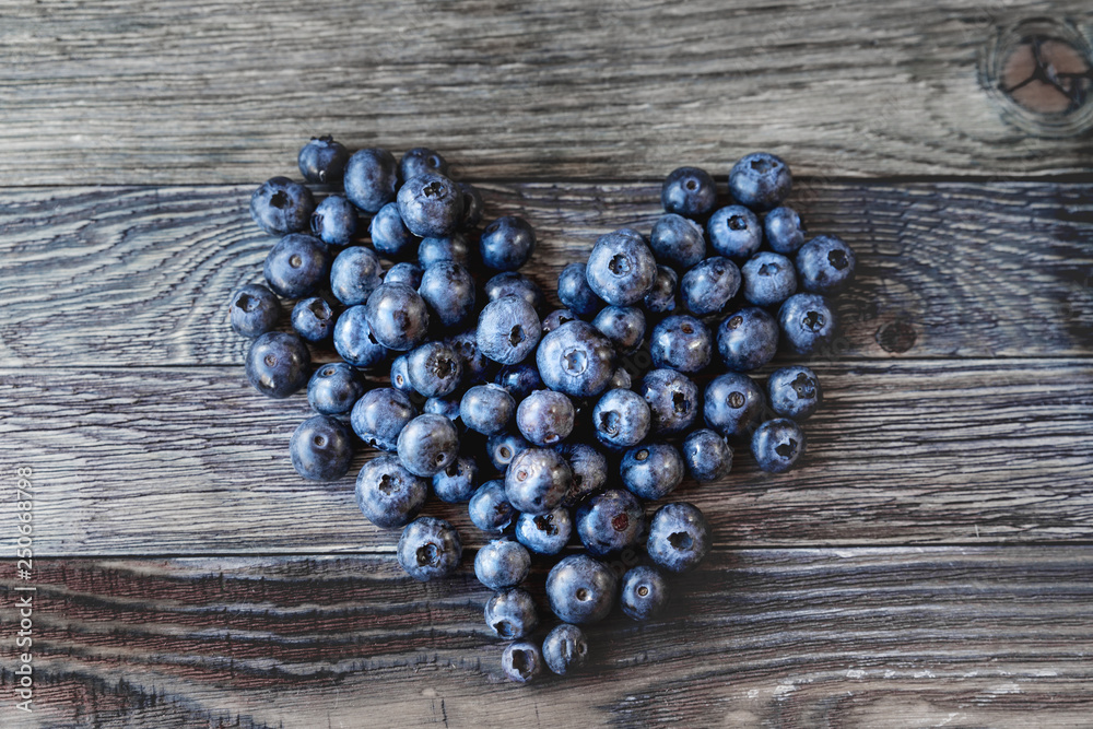 Blueberries on rustic wooden cozy background. Fresh-gathered berries full of vitamins, good for diet nutrition and healthy meals. Heart as a symbol of love and romance. Blueberries on rustic wooden cozy background. Fresh-gathered berries full of vitamins, good for diet nutrition and healthy meals. Heart as a symbol of love and romance.
