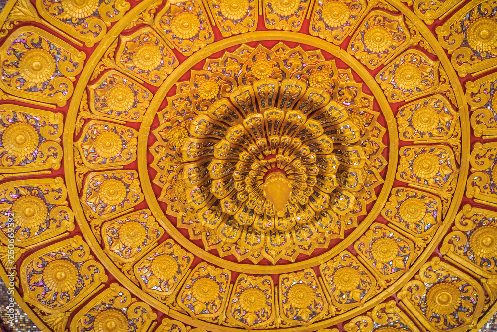 Beautiful golden decorated ceiling in lotus shape with lamp at the Buddhist church, Thailand.