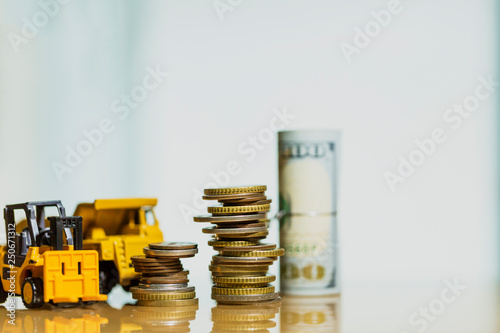 Financial And Macro Economic Concept, pile of coins money stacked on wooden table, with construction vehicle and equipment. Vintage tone.