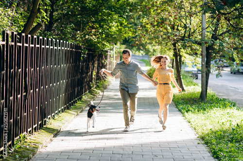 Beautiful cute couple is on a run in the city with their dog jack russel terrier. Beautiful young woman and handsome man are having fun outdoors with jack russel terrier.
