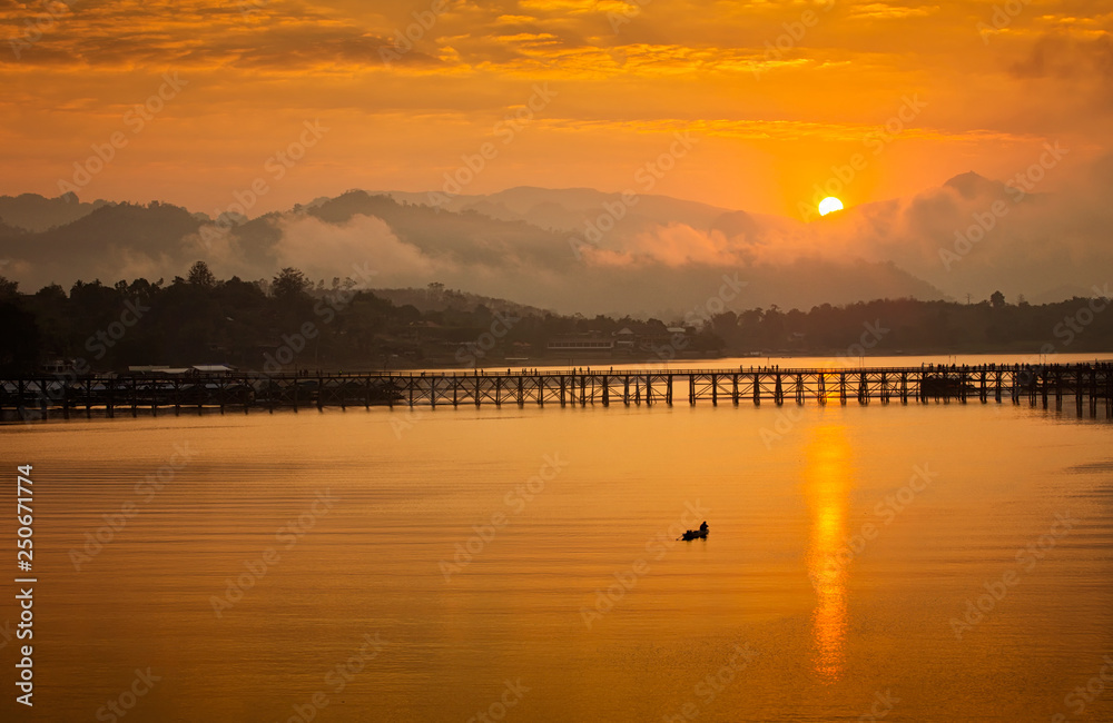 Golden morning light. Mon Bridge is the long wooden bridge. Official name is Attanusorn Bridge. Is the route of the villagers cross to Mon village, Sangkhla Buri, Kanchanaburi, Thailand 24 Jan 2019