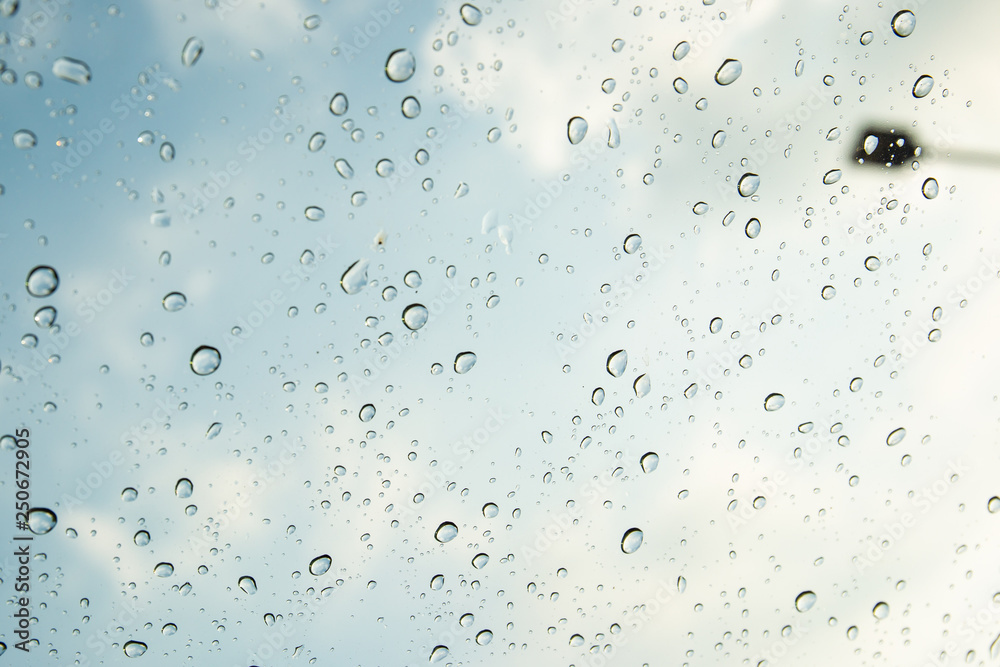 Rain drop on window glass with sky in background close up.