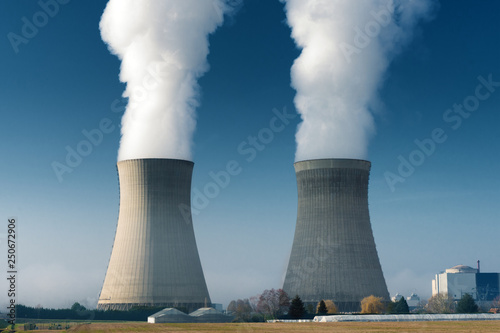 two power plant cooling towers steaming on dark blue sky background photo