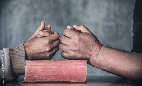 Fotografie Two christian praying together over holy bible on wooden table, prayer meeting concept