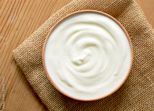Delicious yogurt scene with wooden bowl and sackcloth. Closeup shot of healthy fresh yogurt. Top view.