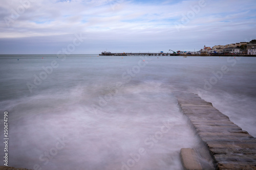 Splashing waves on rock wall in sea with pier