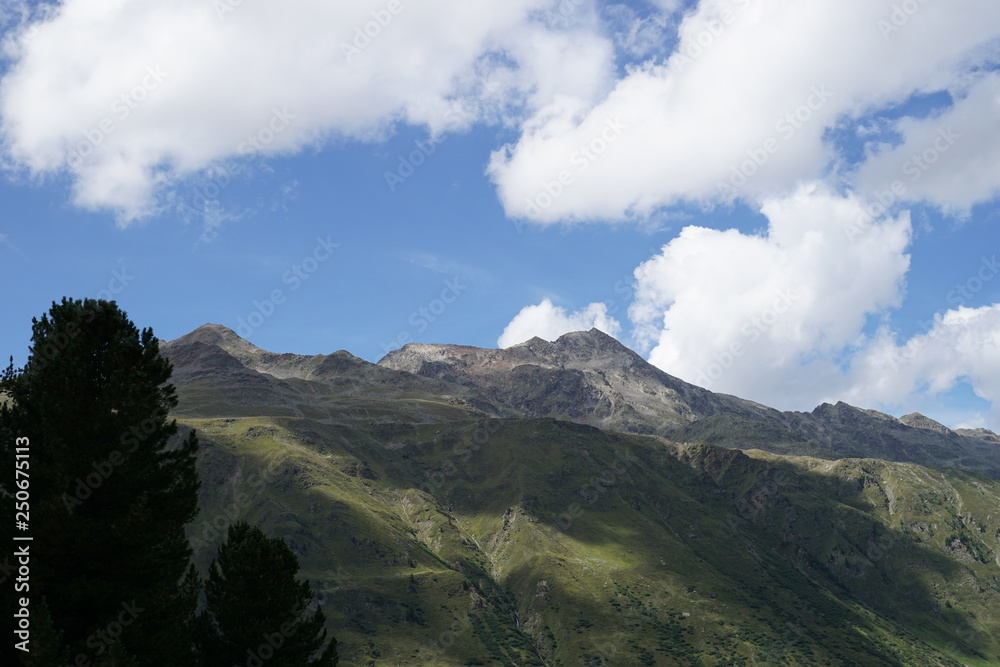 Berglandschaft mit Wolken, Grün, Pflanzen, Felsen und Schnee in Sölden/ Ötztal 