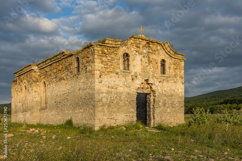 Old Eastern Orthodox church of Saint Ivan Rilski near dam Jrebchevo, Bulgaria. Ruined abandoned church at golden sunset light. photo