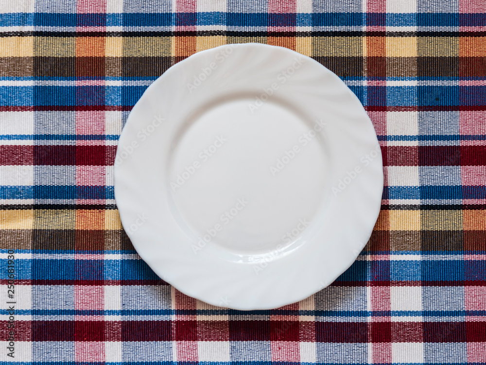 Empty plate on colorful tablecloth in an old wooden table Empty plate on colorful tablecloth in an old wooden table