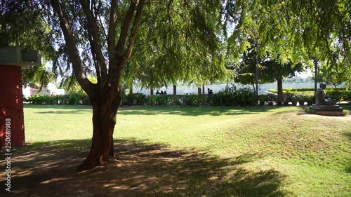 Panning shot of the gardens in Sabarmati Gandhi ashram with as statue of Mahatma Gandhi in meditation