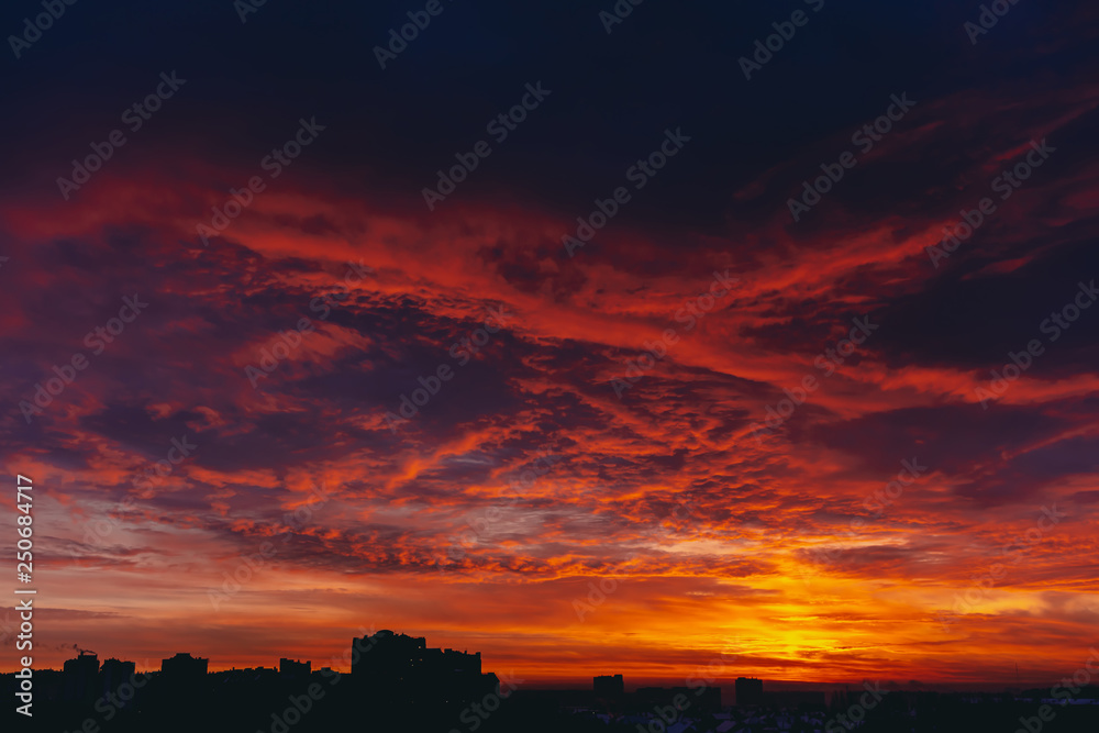 Fiery red blood vampire dawn. Amazing warm dramatic fire blue dark cloudy sky. Orange sunlight. Atmospheric background of sunrise in overcast weather. Hard cloudiness. Storm clouds warning. Copy space