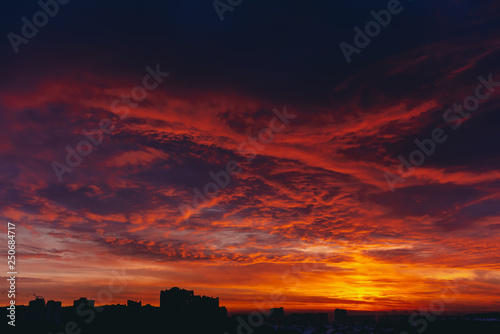 Fiery red blood vampire dawn. Amazing warm dramatic fire blue dark cloudy sky. Orange sunlight. Atmospheric background of sunrise in overcast weather. Hard cloudiness. Storm clouds warning. Copy space © Daniil
