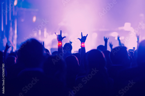 Concert, event or party concept. People with hands up near the scene, spotlight, colored blue light.