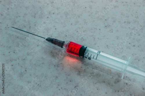 Syringe with red solution on white background