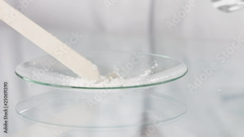 Scientist spreading unkown white powder on petri dish