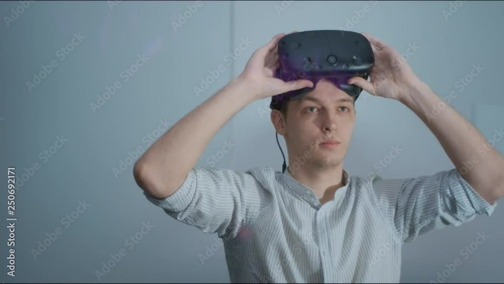 The young guy puts on virtual reality glasses and starts downloading the file, looks around. Close up. The future of architecture and construction industry. Loft-office. Red epic. 4K The young guy puts on virtual reality glasses and starts downloading the file, looks around. Close up. The future of architecture and construction industry. Loft-office. Red epic. 4K