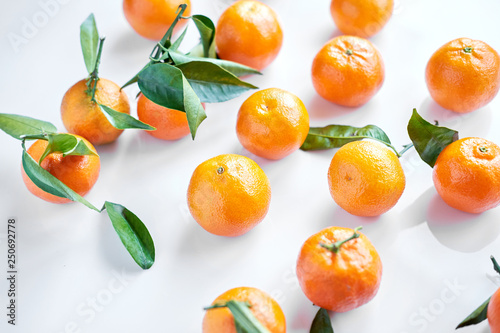 Group of orange fresh tangerines with green leaves lie on a white background. Closeup.