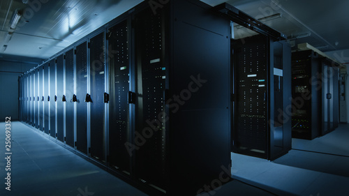 Shot of a Working Data Center With Rows of Rack Servers. Led Lights Blinking and Computers are Working. Dark Ambient Light.