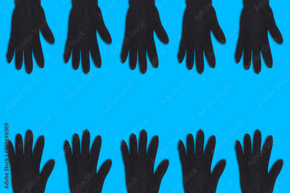 Two horizontal rows of black warm woolen gloves on blue background with copy space for your text. Top view Two horizontal rows of black warm woolen gloves on blue background with copy space for your text. Top view