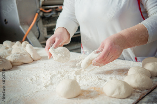 Woman baker make buns from dough