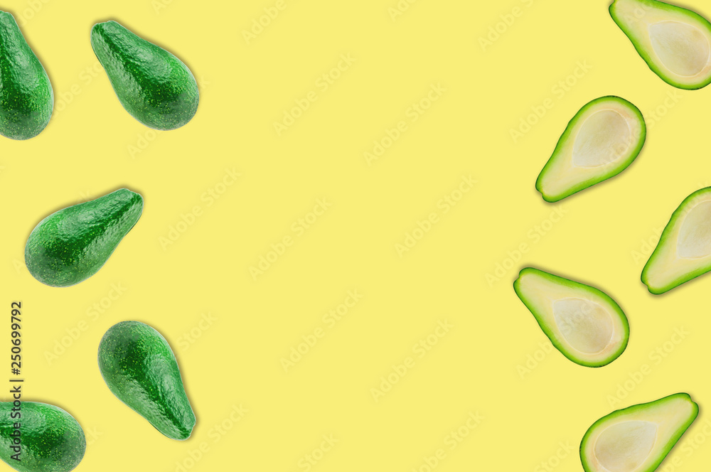 Scattered fresh wholes and halves of organic avocado without kernels on yellow table in kitchen or market. Top view. Cooking concept. Copy space for your text Scattered fresh wholes and halves of organic avocado without kernels on yellow table in kitchen or market. Top view. Cooking concept. Copy space for your text