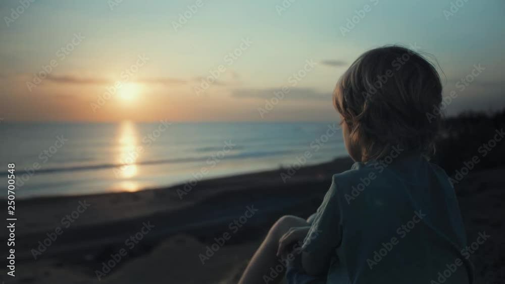 Child admiring beautiful sunset on shore. Looking at ocean view, thinking about life, dreaming. Happy childhood. Enjoying afternoon peace and nature. Quiet, calm mood. Vacation travel Child admiring beautiful sunset on shore. Looking at ocean view, thinking about life, dreaming. Happy childhood. Enjoying afternoon peace and nature. Quiet, calm mood. Vacation travel