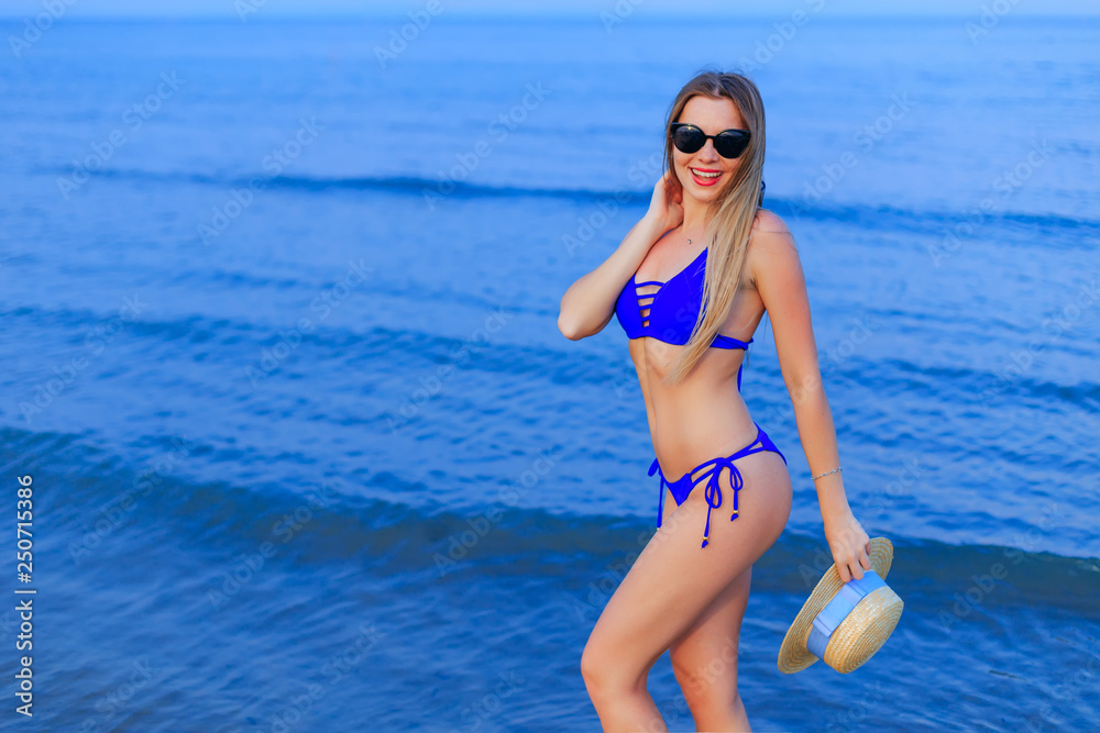 Pretty girl with sunglasses in blue swimsuit poses on the backgr Pretty girl with sunglasses in blue swimsuit poses on the backgr
