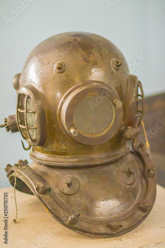 Antique metal scuba helmet, heavy diving equipment with air supply. Vintage old diving helmet in brass and steel for deep sea diving.