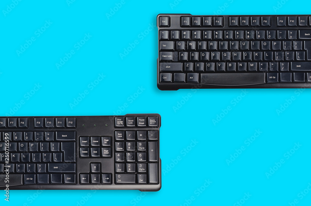 Two black plastic wireless computer keyboards on blue office table. Top view. Copy space for your text. Business concept