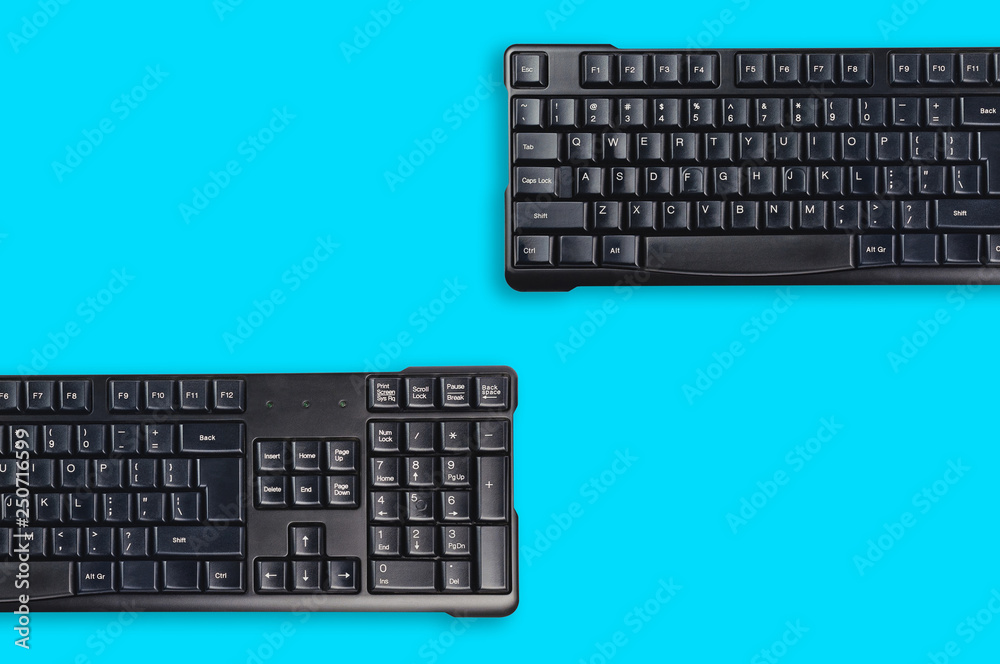 Two black plastic wireless computer keyboards on blue office table. Top view. Copy space for your text. Business concept Two black plastic wireless computer keyboards on blue office table. Top view. Copy space for your text. Business concept