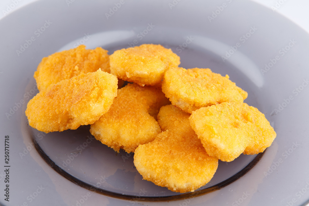 Chicken nuggets with cheese on a glass plate.