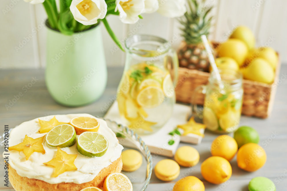 Fototapeta premium Lemonade and flowers tulips on table. Mason jar glass of lemonade with lemons and straw. Copy space. Fruits and macaroons on the table. The concept of spring and summer season.Healthy Food and Drink