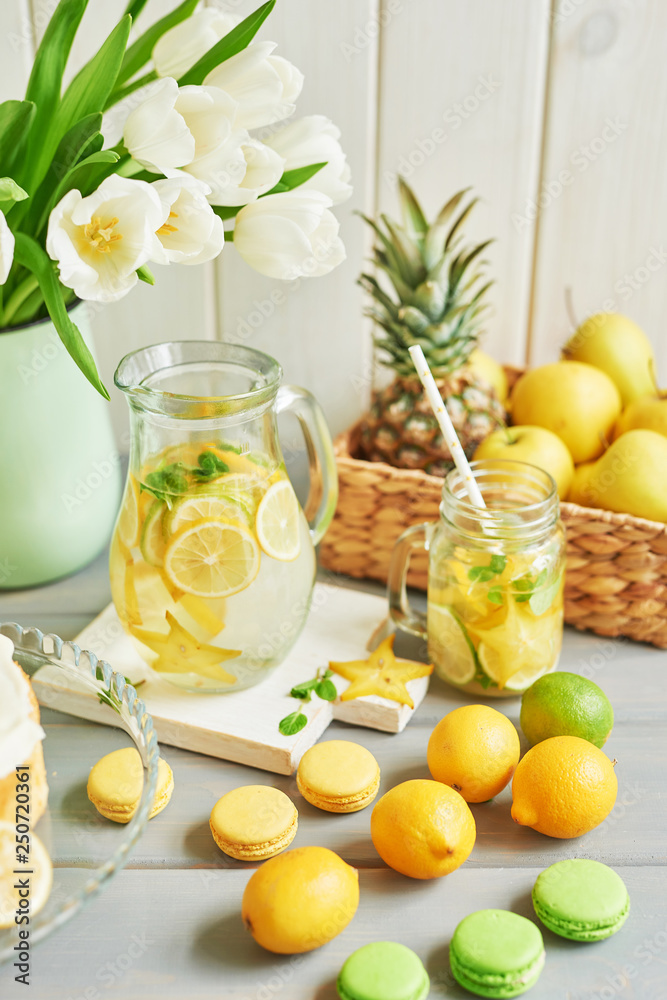 Lemonade and flowers tulips on table. Mason jar glass of lemonade with lemons and straw. Copy space. Fruits and macaroons on the table. The concept of spring and summer season.Healthy Food and Drink Lemonade and flowers tulips on table. Mason jar glass of lemonade with lemons and straw. Copy space. Fruits and macaroons on the table. The concept of spring and summer season.Healthy Food and Drink
