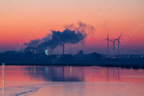 Colorful sunrise with industry buildings and wind turbines