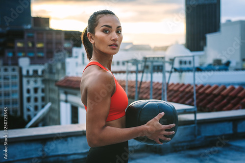 Portrait of a woman standing on rooftop holding a medicine ball