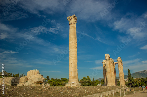 destroyed marble columns ruins of ancient temple in park outdoor environment on vivid blue sky background, open air museum place