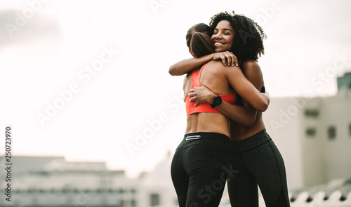 Smiling athlete giving a hug to her friend during workout