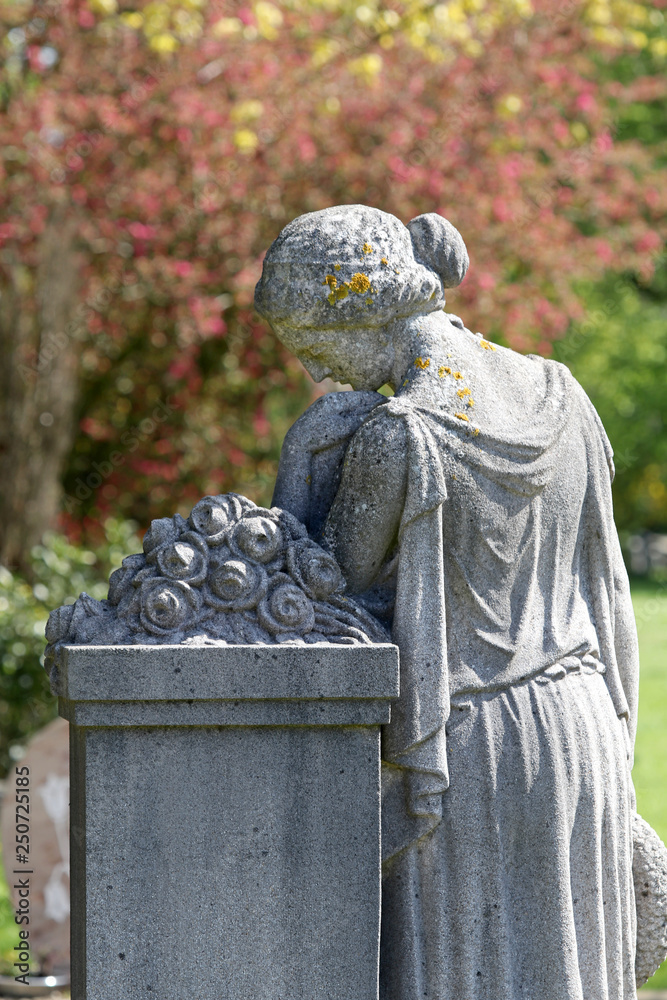 Obraz premium sculpture and blooming trees at municipal cemetery at springtime, Amsterdam, The Netherlands
