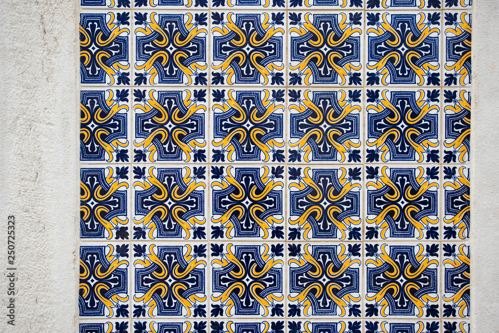 Old wall with traditional Portuguese decor tiles azulezhu in blue and yellow tones.