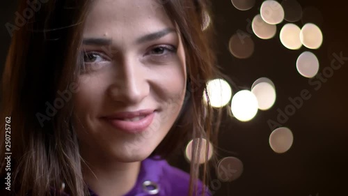 Closeup portrait of young seductive caucasian female smiling and looking straight at camera with night lights on the background photo