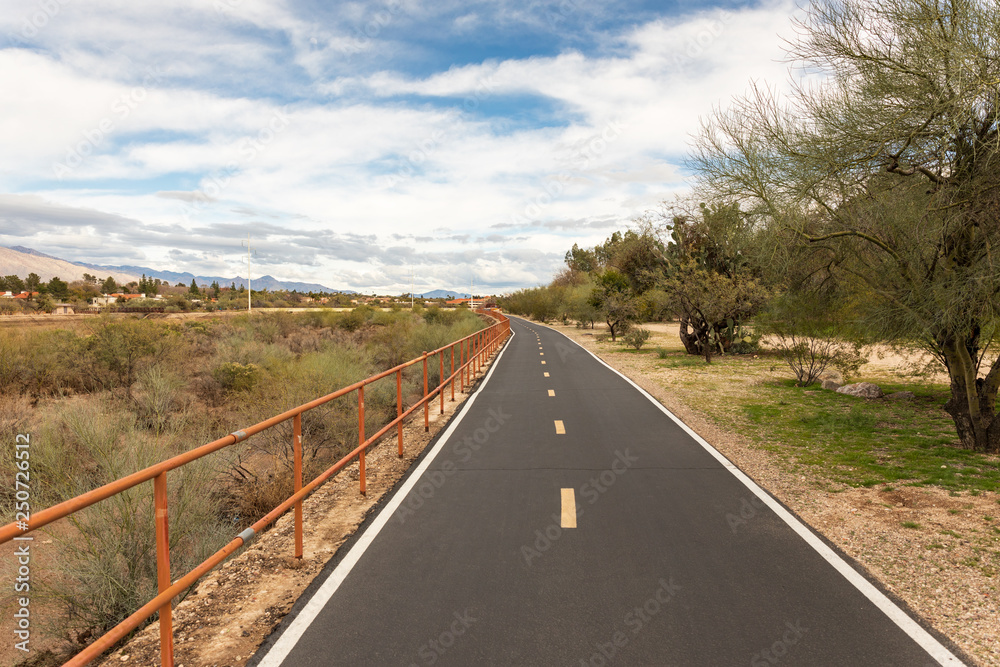 Paved bike lane next to dry river bed in desert