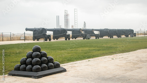 A row of heavy Guns and saluting battery in the upper barrakka gardens. In the foreground a pyramid of cannonballs. Valletta, Malta, Europe
