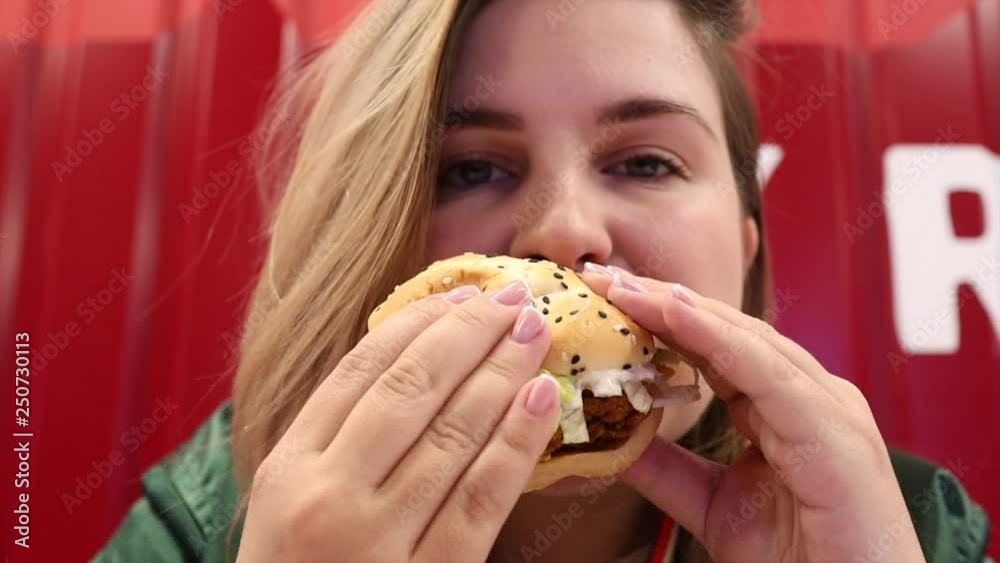 Young woman enjoying delicious burger with eyes closed in fast food cafe Young woman enjoying delicious burger with eyes closed in fast food cafe