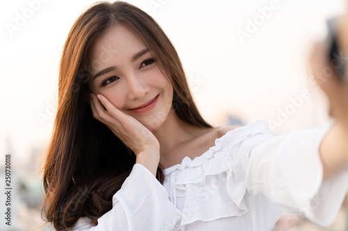 Closeup portrait of inspired caucasian Asian smiling and taking selfie on roof top. Concept woman healthy and lifestyle. photo