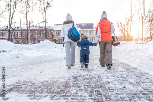 Woman mother with girlfriend parents holding boy son for 2-3 years hand, winter along city road. Back view. Concept caring support, parental child care, proper parenting. Free space for text.