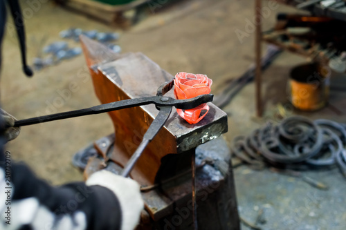 Blacksmith forges steel rose on the anvil