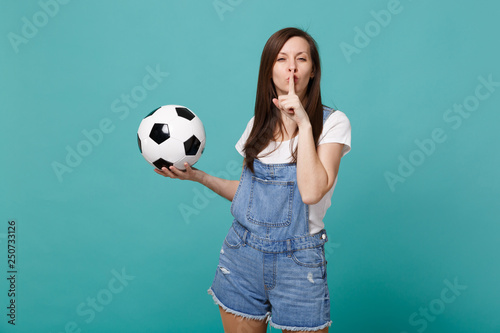 Pretty woman football fan support favorite team with soccer ball say hush be quiet with finger on lips shhh gesture isolated on blue turquoise background. People emotions sport family leisure concept. © ViDi Studio