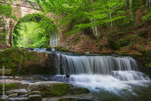 Waterfall under Bridge with long exposure. Summer time with green trees. Shot from Bulgaria