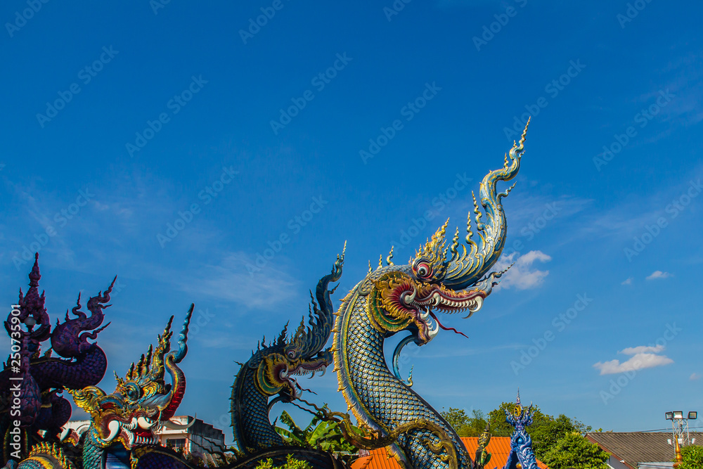 Beautiful blue naga sculpture with blue sky and white cloud on the sunny day at the public temple, Wat Rong Sua Ten, Chiang Rai, Thailand. Naga is a very great snake, found in the Buddhism temples. Beautiful blue naga sculpture with blue sky and white cloud on the sunny day at the public temple, Wat Rong Sua Ten, Chiang Rai, Thailand. Naga is a very great snake, found in the Buddhism temples.