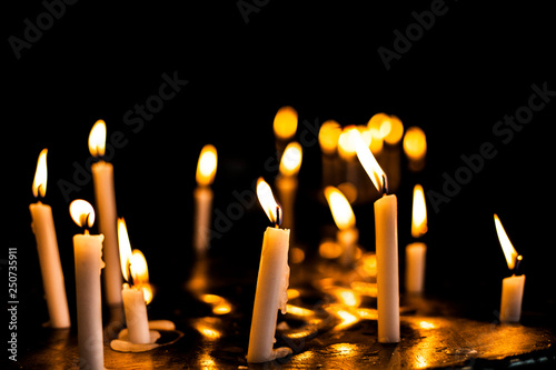 Candle flames in the Christian church. Group of yellow candles at the church. Dark mood with burnt candles